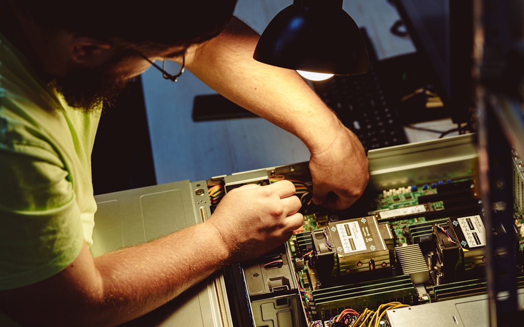 Man repairing a computer server under a lamp.